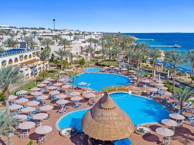 Großes Hotelresort mit mehreren Pools, Sonnenschirmen und Blick auf das Meer bei klarem Wetter.