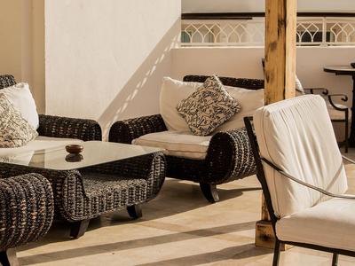 Gemütliche Lounge mit Rattansessel und Tisch auf sonniger Hotelterrasse.