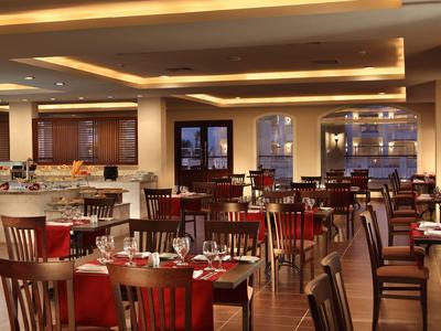 Geräumiges Restaurant mit Holztischen und Stühlen, gedeckten Tischen und warmem Licht.