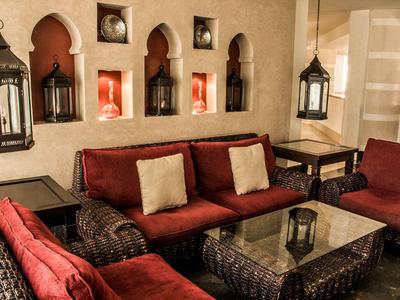 Gemütlicher Lounge-Bereich mit roten Sofas, Kissen und orientalischen Laternen in einem Hotel.