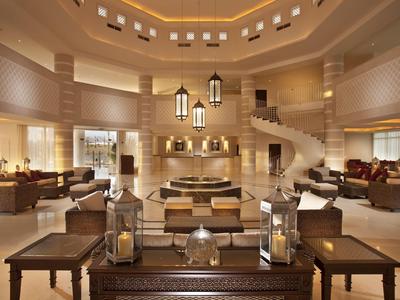 Luxuriöse Hotellobby mit eleganten Sitzbereichen, warmem Licht und zentralen Laternen.