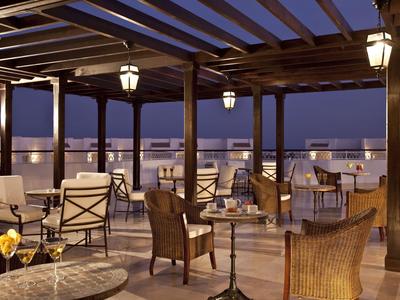 Dachterrasse mit Tischen und Stühlen unter Holzpergola bei Abenddämmerung.