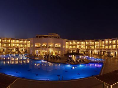 Hotel bei Nacht mit beleuchtetem Pool und warmem, einladendem Licht.