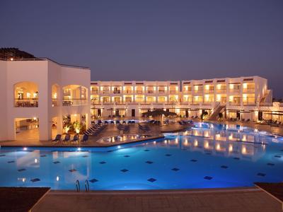 Hotel mit beleuchtetem Poolbereich und modernen, mehrstöckigen Zimmern bei Nacht.