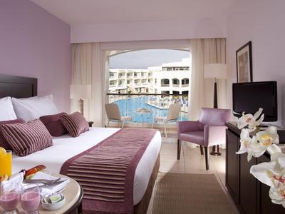 Hotelzimmer mit Blick auf den Pool, modernen Möbeln und einem komfortablen Doppelbett.