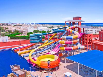 Bunter Wasserpark auf einem Hotel mit Wasserrutschen und blauen Schattendächern nahe dem Meer.
