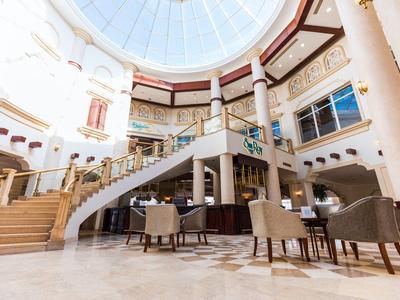 Lounge d'hotel luminosa e spaziosa con poltrone accoglienti e una cupola di vetro.
