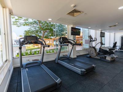 Palestra luminosa con tapis roulant e vista su alberi e strada attraverso grandi finestre.