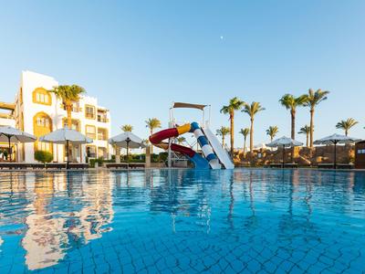 Piscina con scivolo e ombrelloni davanti a un hotel sotto un cielo sereno.