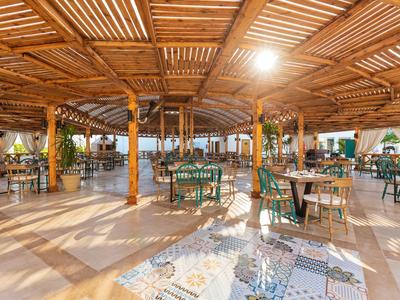 Un'ampia sala pranzo dell'hotel illuminata dal sole con tetto in legno e sedie verdi.