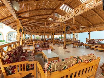 Padiglione aperto dell'hotel con mobili in legno e cuscini decorati, vista sul mare.