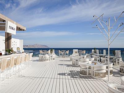 Grande terrasse avec mobilier blanc et vue sur la mer sous un ciel bleu.