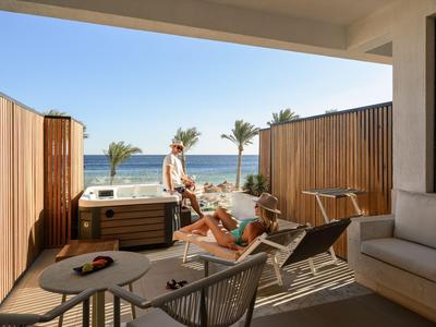 Balcon avec panneaux en bois, vue sur la mer et invités détendus dans un resort.