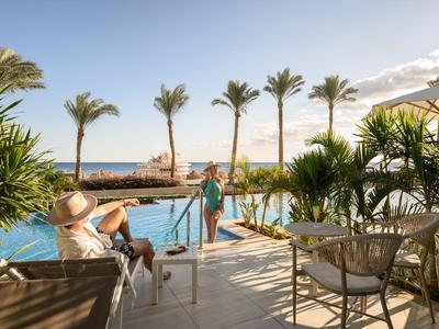 Terrazza con piscina, palme e vista mare in una giornata di sole in hotel.