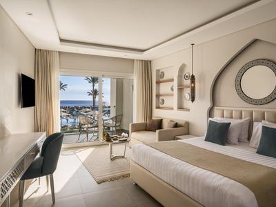Chambre d'hôtel moderne avec lit double, coin salon et balcon avec vue sur la mer.