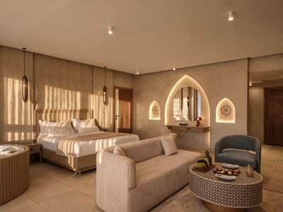Camera d'hotel moderna con letto grande, divano, poltrona e specchi decorativi in tonalità calde.