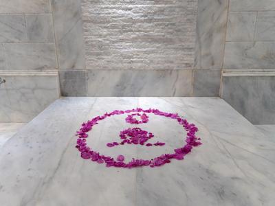 Weißer Marmortisch mit lila Blüten, dekoriert im Yoga-Symbol-Stil in einem Spa-Bereich.