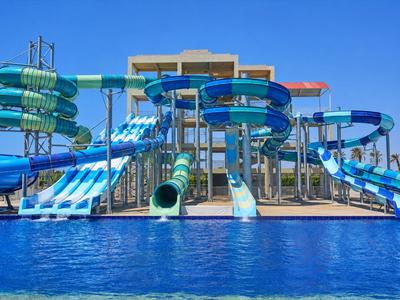 Große Wasserrutschen und ein Pool vor blauem Himmel in einem Ferienresort.