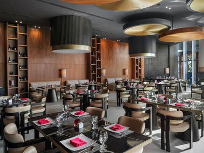 Modernes Hotelrestaurant mit stilvollen Holzmöbeln, elegant gedeckten Tischen und dezenter Beleuchtung.