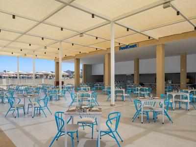 Überdachter Außenbereich mit blauen Stühlen und Tischen, ideal für Hotelgäste.