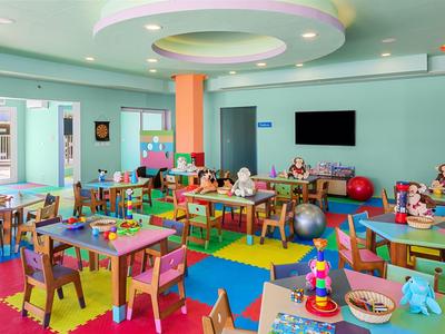 Bunter Spielraum mit Tischen, Stühlen und Spielsachen im Hotel für Kinder.