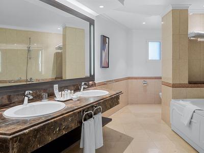 Modernes Badezimmer mit zwei Waschtischen, großer Badewanne und beigem Fliesenboden.