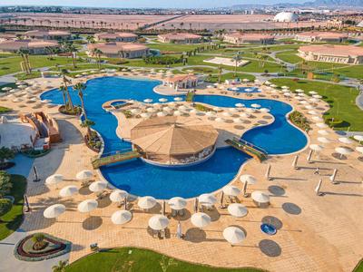 Großer Hotelpool mit zahlreichen Sonnenschirmen und umliegender Landschaft.