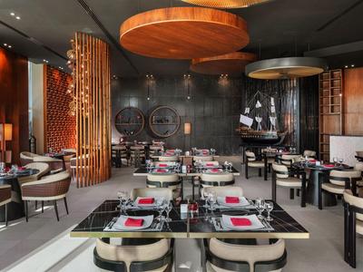 Moderne Hotellounge mit eleganten Tischen, bequemen Stühlen und warmem Lichtdesign.