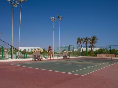 Ein Tennisplatz unter klarem blauem Himmel mit einem Paar, das auf der Bank sitzt.
