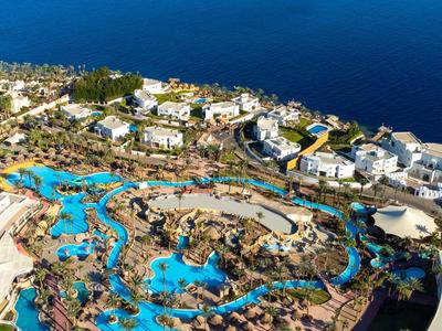 Blick auf ein Hotelresort mit mehreren Pools und Blick auf das Meer im Hintergrund.