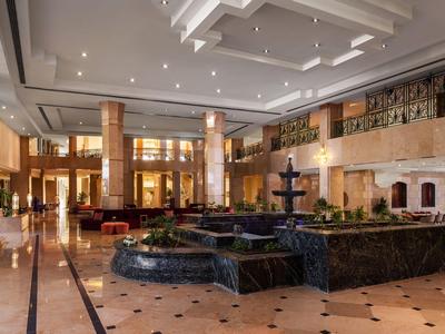 Großer Hotel-Lobbybereich mit Marmorboden und zentralem Springbrunnen im modernen Design.