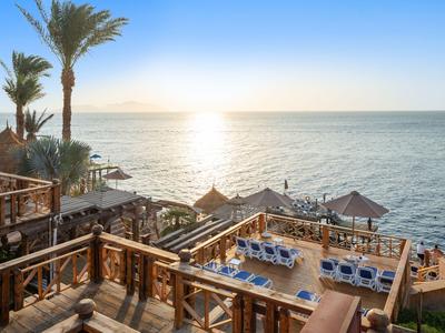 Sonnige Hotelterrasse mit Liegestühlen und Blick auf das ruhige Meer am Nachmittag.