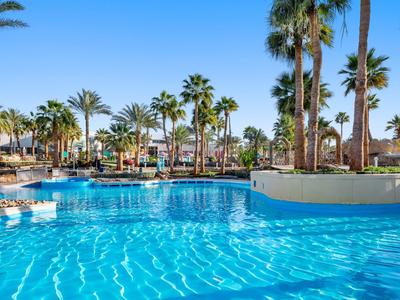 Großer Außenpool mit klarem Wasser und Palmen in einem sonnigen Hotelanlage.
