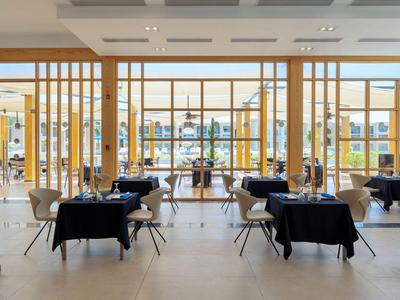 Modernes Restaurant mit Holzelementen, schwarzen Tischdecken und einem hellen, offenen Raum.