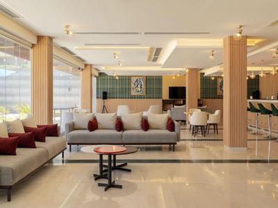 Lounge d'hotel luminosa e moderna con comodi divani, tavoli e grandi finestre.