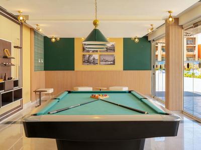 Moderner Poolraum mit grünem Billardtisch, Wandregalen, und großem Fenster zum Außenbereich.