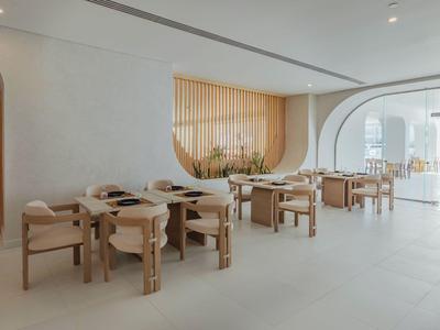 Heller, moderner Speiseraum mit Holz- und beigen Farbtönen, minimalistischer Einrichtung und großen Sitzbereichen.