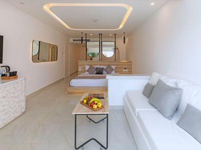 Helles Hotelzimmer mit Doppelbett, Sofa, Tisch mit Obst und modernem Design.
