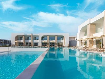 Moderner Hotelpool mit klar blauem Wasser und Sonnenschirmen unter blauem Himmel.