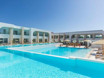 Moderner Hotelpool mit klarem blauem Wasser, umgeben von weißen Gebäuden und Sonnenliegen.