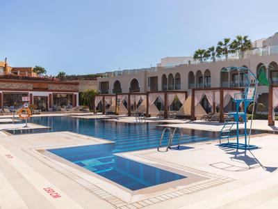 Moderner Hotelpool mit Liegestühlen und weißen Sonnenschirmen bei klarem Himmel.