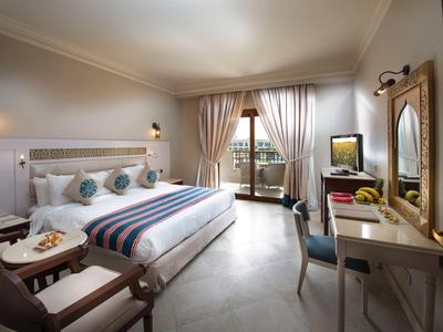 Helles Hotelzimmer mit großem Bett, Sitzbereich und Balkon mit Meerblick.