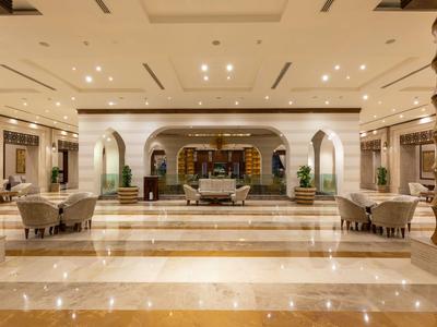 Elegante Hotellobby mit Marmorboden, Sofas und warm beleuchteten, modernen Details.