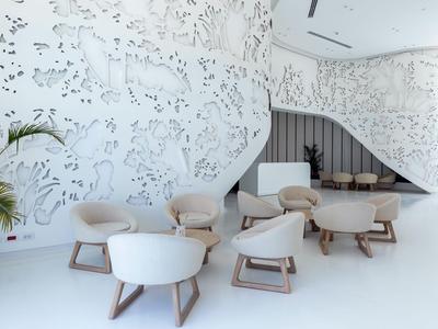 Area lounge moderna e luminosa con arredamento bianco e arte murale dettagliata in un hotel.