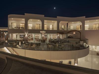 Terrazza dell'hotel con sedie e tavoli di notte sotto un cielo notturno sereno con luna visibile.