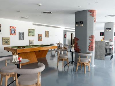 Area lounge moderna con tavolo da biliardo, sedute e bar in un ambiente luminoso.