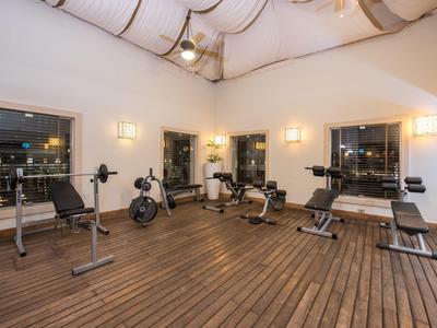 Ein moderner Fitnessraum mit Holzfußboden und verschiedenen Trainingsgeräten zeigt eine entspannte Atmosphäre.