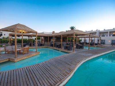 Modern pool area with wooden walkways, gazebos, and lounge furniture at a hotel resort.