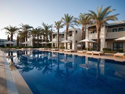 Moderner Hotelkomplex mit Pool und Palmen in ruhiger Urlaubsatmosphäre bei Sonnenuntergang