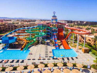 Parque acuático versátil con toboganes coloridos y piscinas frente a hoteles bajo cielo despejado.